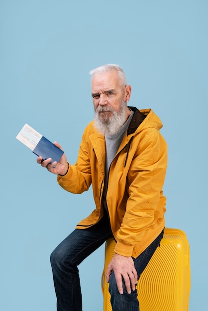 Älterer Mann mit Reisepass, der auf Gepäck sitzt