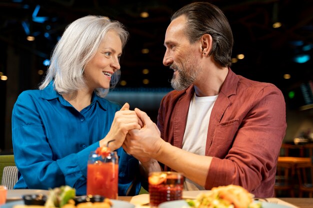 Älterer Mann überrascht seine Freundin und hält ihre Hände in einem Restaurant