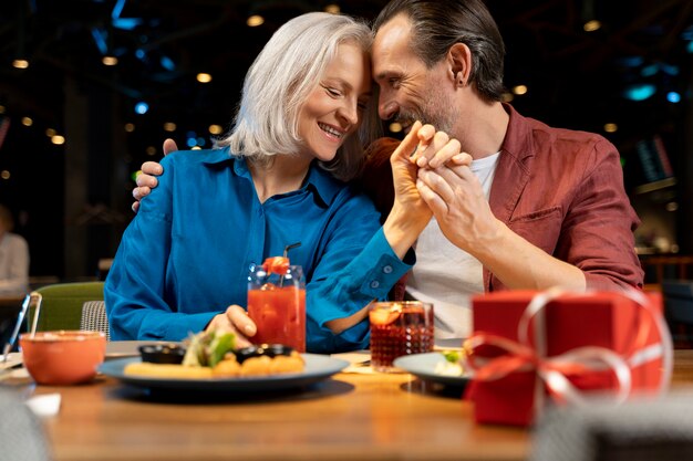 Älterer Mann überrascht seinen Freund mit einem Geschenk in einem Restaurant