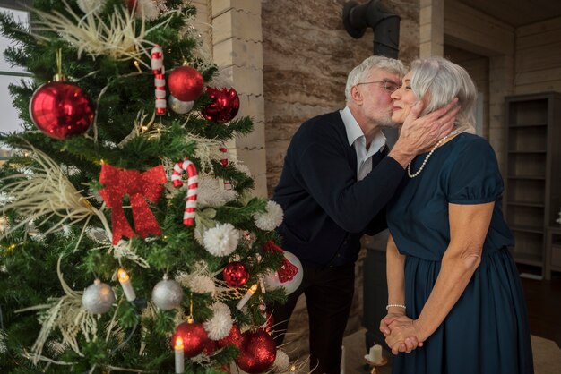 Älterer Mann und Frau neben dem Weihnachtsbaum