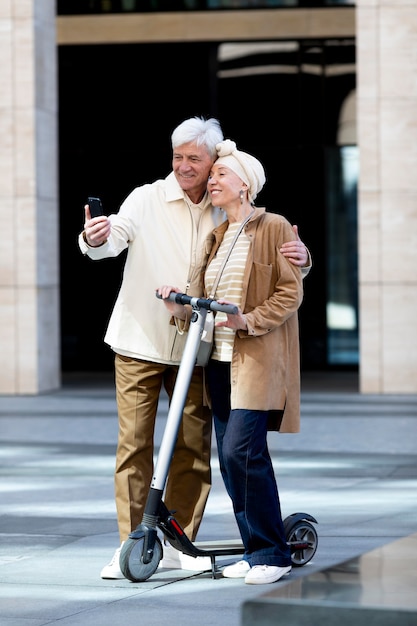 Älteres Paar, das einen Elektroroller in der Stadt fährt und Selfie macht