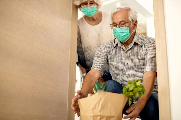 Älteres Paar, das während der Coronavirus-Epidemie kontaktlose Lebensmittellieferungen erhält