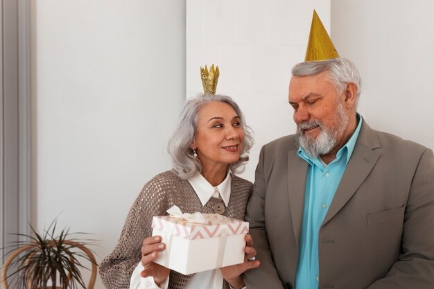 Älteres Paar der mittleren Aufnahme, das mit Geschenk feiert