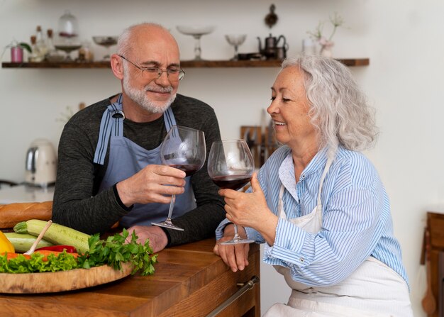 Älteres Paar kocht gemeinsam in der Küche und trinkt Wein