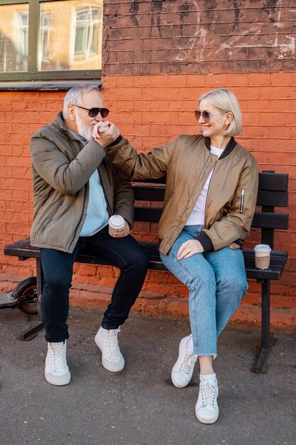 Älteres Paar mit voller Aufnahme, das draußen auf einer Bank sitzt