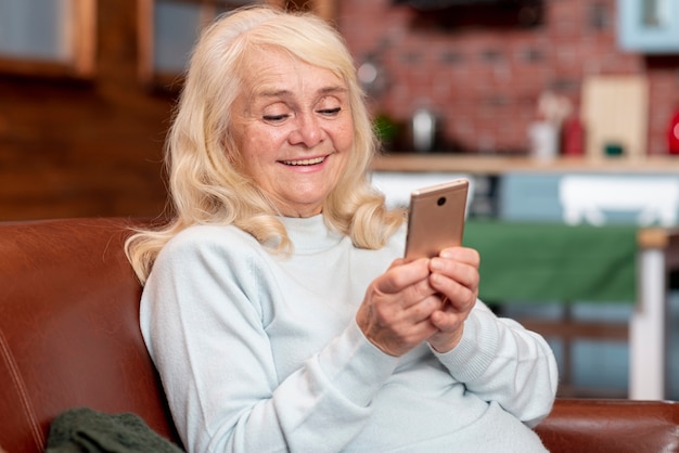 Älteres weibliches schauendes Telefon