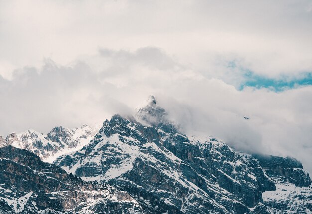 Luftaufnahme der schönen felsigen schneebedeckten Berge, die in den Wolken bedeckt sind