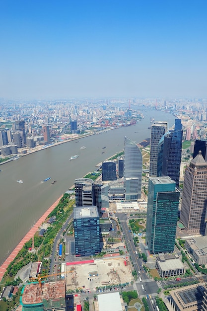 Luftaufnahme der Stadt Shanghai mit städtischer Architektur über Fluss und blauem Himmel am Tag.