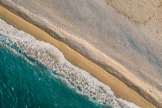 Luftaufnahme des Sandes, der das Meerwasser und die Wellen trifft