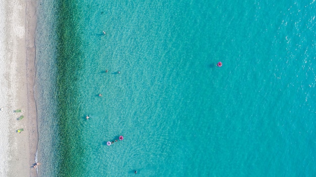 Luftaufnahme des Sandstrandes mit schwimmenden Touristen.