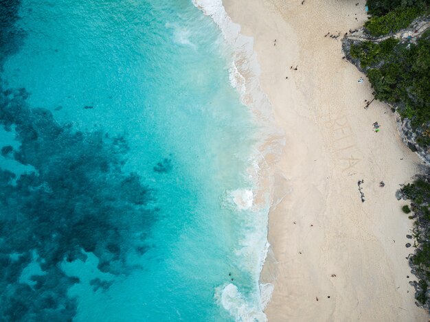 Luftaufnahme des Strandes, umgeben von Grün und Meer