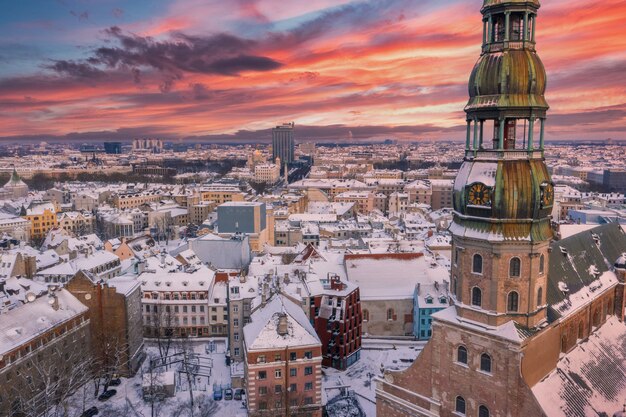 Luftaufnahme des wunderschönen Sonnenuntergangs über der schneebedeckten Stadt Riga mit dem Fluss Daugava und der Innenstadt