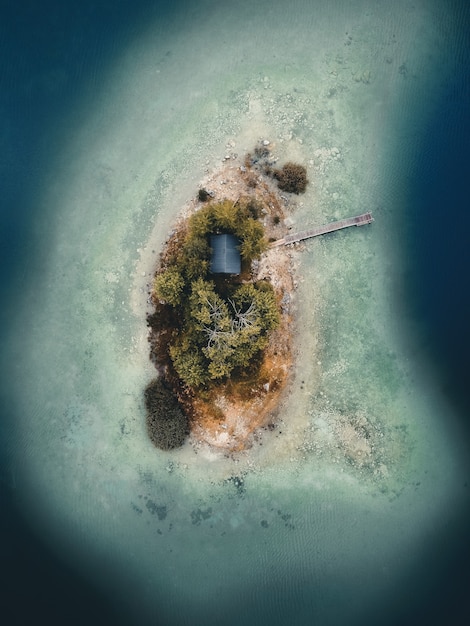 Luftaufnahme einer Insel mit Bäumen und eines Hauses mit einem hölzernen Pier mitten im Nirgendwo