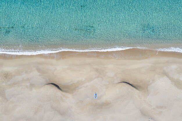 Luftaufnahme einer Person, die am Sandstrand in der Nähe des Meeres liegt