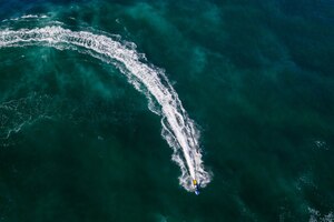 Kostenloses Foto luftaufnahme einer person, die im hellgrünen meerwasser jetski fährt