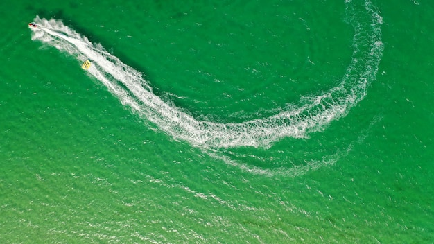 Luftaufnahme eines Bootes mit einer Person, die an einem daran befestigten Seil surft