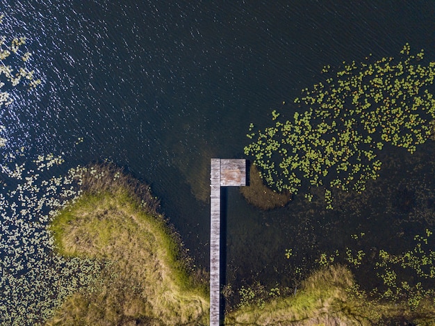 Luftaufnahme eines hölzernen Weges über dem Wasser nahe einem grasbewachsenen Ufer