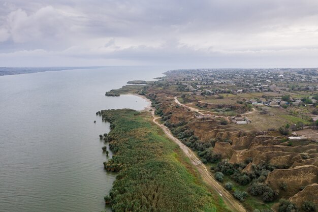 Luftaufnahme eines Weges entlang des riesigen Sees mit schönen Sanddünen und grünem Ufer