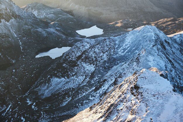 Luftaufnahme von schneebedeckten Bergen nahe Teichen am Tag