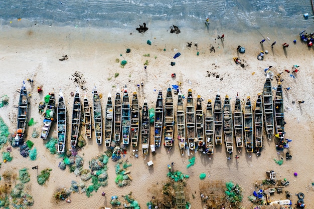 Luftaufnahme von verschiedenfarbigen Booten an einem Sandstrand mit dem Meer in der Nähe