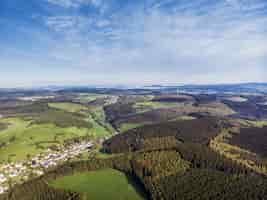 Kostenloses Foto luftbildaufnahme von schönen grünen feldern und häusern der landschaft an einem sonnigen tag