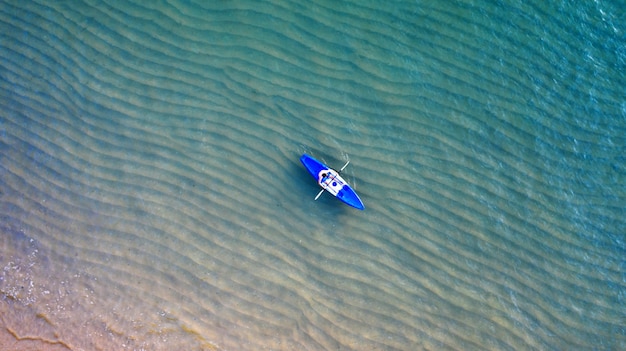 Luftdraufsicht von kayak fahren um meer mit blauem wasser des smaragdwassers und wellenschaum