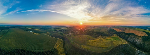 Luftdrohne-Panoramablick auf die Natur in Moldawien bei Sonnenuntergang. Dorf, weite Felder, Täler