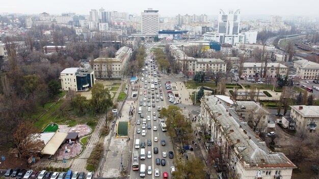 Luftdrohnen-Panoramablick auf Chisinau, Straße mit mehreren Wohn- und Geschäftsgebäuden, Straße mit mehreren fahrenden Autos, Park mit kahlen Bäumen