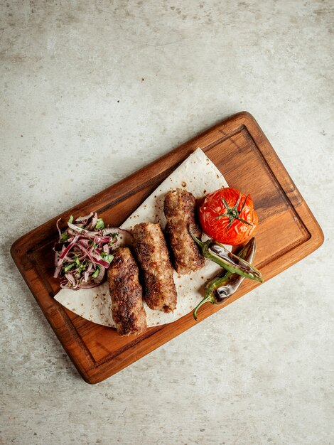 Lule Kebab mit gebratenen Tomaten und geschnittenen Zwiebeln