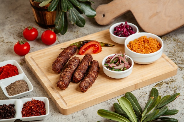 Lule Kebab serviert mit Bulgur Bowl Zwiebelsalat und Rotkohlgurken