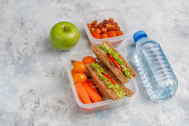 Lunchbox mit Sandwich, Gemüse, Frucht auf Weiß.