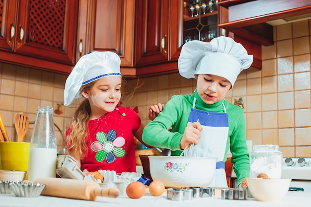 Lustige Familie lustige Kinder bereiten den Teig vor, backen Kekse in der Küche