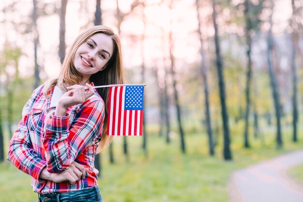 Lustige hübsche Frau, die mit amerikanischer Flagge aufwirft