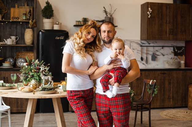 Lustige kaukasische Familie im Familienlook mit weißem T-Shirt und roter Hose. Vater hält Baby.