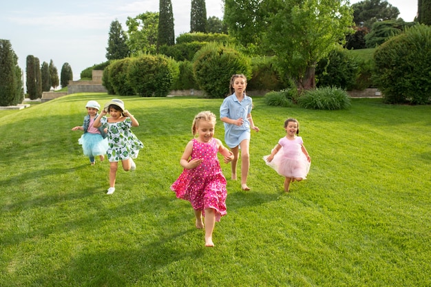 Lustige Starts. Kindermode-Konzept. Gruppe von jugendlichen Jungen und Mädchen, die am Park laufen