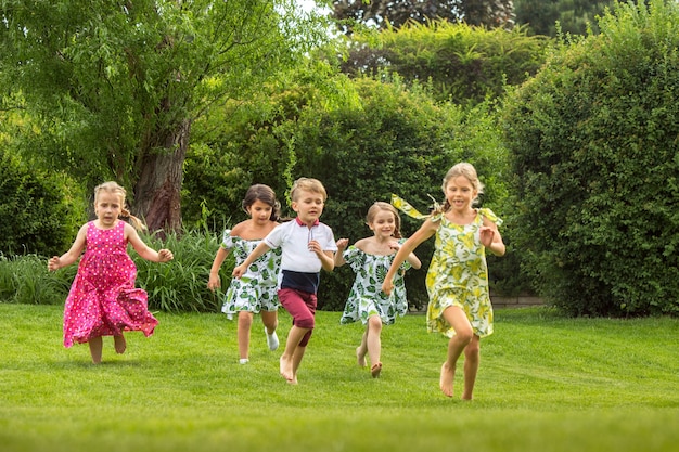 Lustige Starts. Kindermode-Konzept. Gruppe von jugendlichen Jungen und Mädchen, die am Park laufen