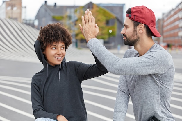 Lustige Teenager gemischter Rassen mit freundlichem Gesichtsausdruck geben sich gegenseitig High Five, stimmen zu, etwas zu tun