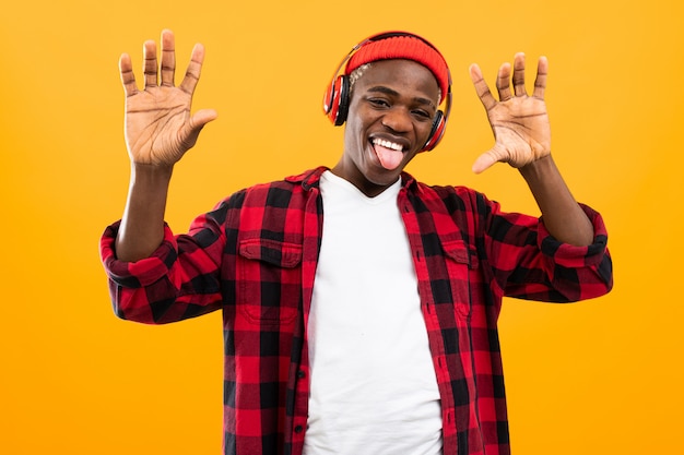 Lustiger amerikanischer schwarzer mann mit grimasse auf seinem gesicht hört musik auf gelb