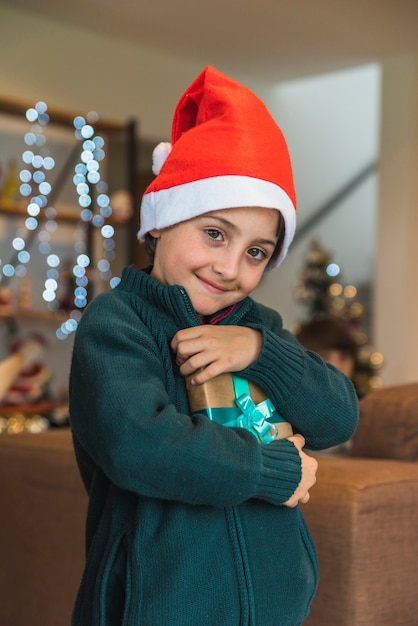 Lustiger Junge im Weihnachtshut mit Präsentkarton