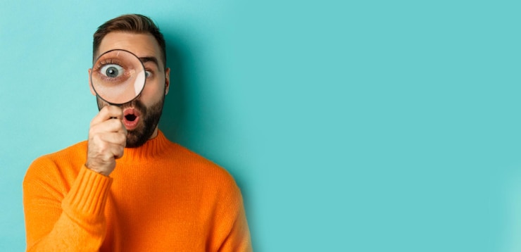 Kostenlose Foto lustiger mann, der durch lupe schaut und etwas sucht oder untersucht, das in orange s steht