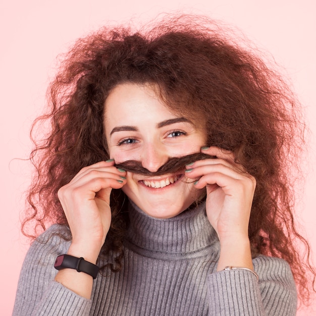 Lustiges Brunettemädchenporträt auf rosa Hintergrund