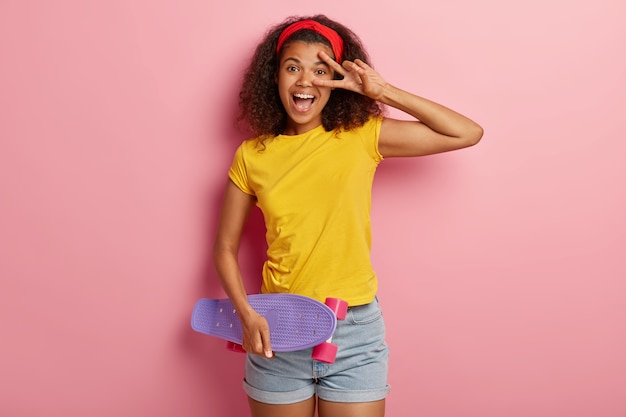 Lustiges junges Mädchen mit dem lockigen Haar, das im gelben T-Shirt aufwirft