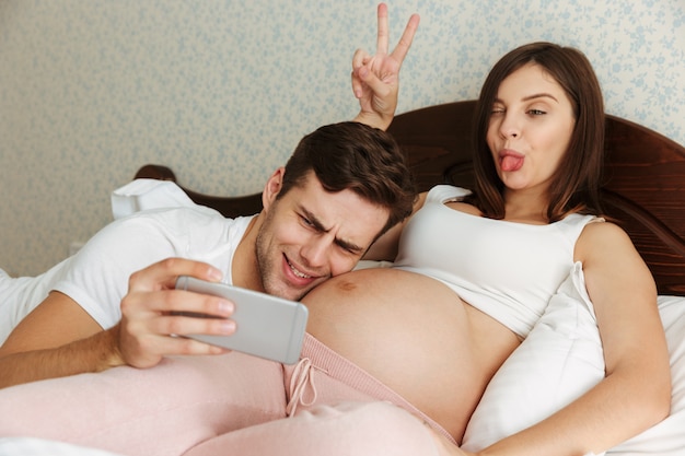 Lustiges junges schwangeres Paar, das selfie nimmt