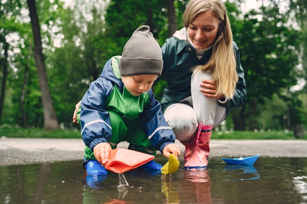 Kostenloses Foto lustiges kind in den regenstiefeln, die in einem regenpark spielen