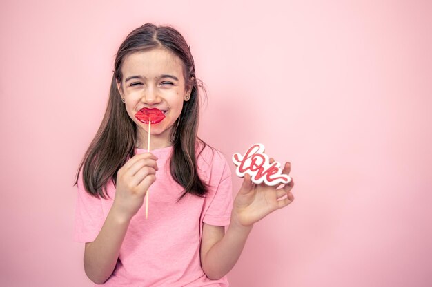 Lustiges kleines Mädchen mit einem lippenförmigen Lutscher in ihren Händen kopieren Raum