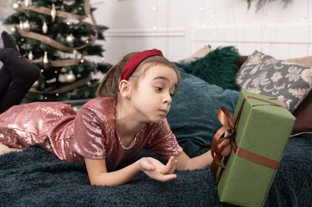 Lustiges kleines Mädchen mit einer Weihnachtsgeschenkbox