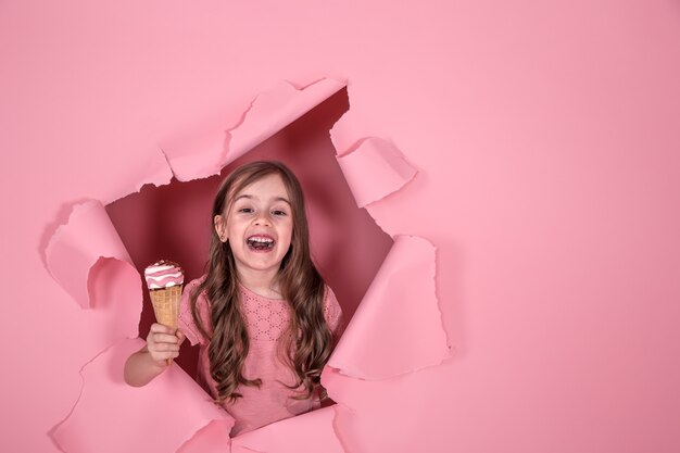 lustiges kleines Mädchen mit Eiscreme auf farbigem Hintergrund