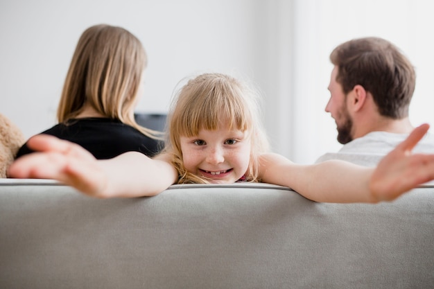 Lustiges Mädchen auf Couch nahe Eltern