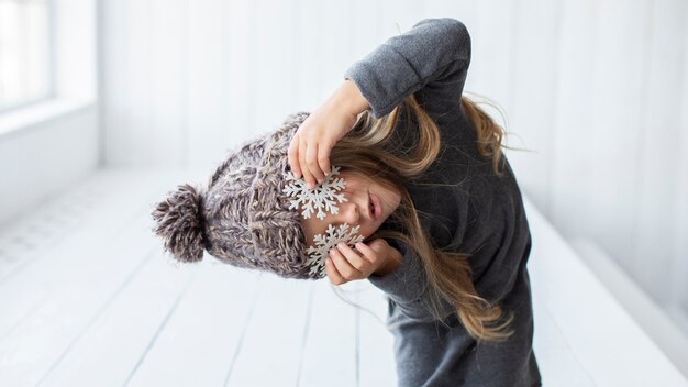 Lustiges Mädchen, das ihre Augen mit Schneeflocken bedeckt