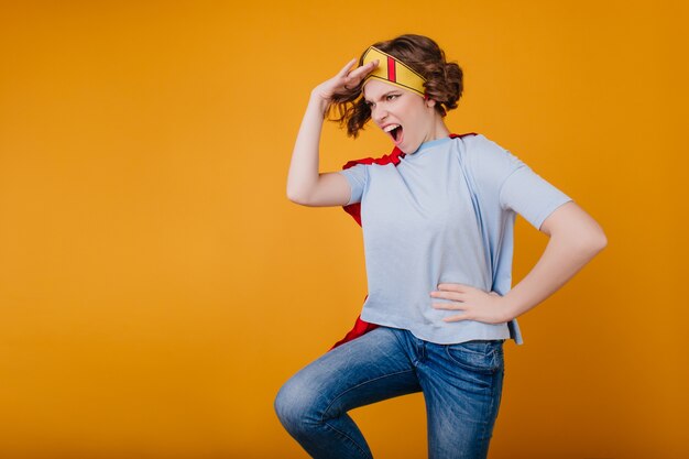 Lustiges Mädchen in der gelben Papierkrone, die auf Fotoshooting herumalbert